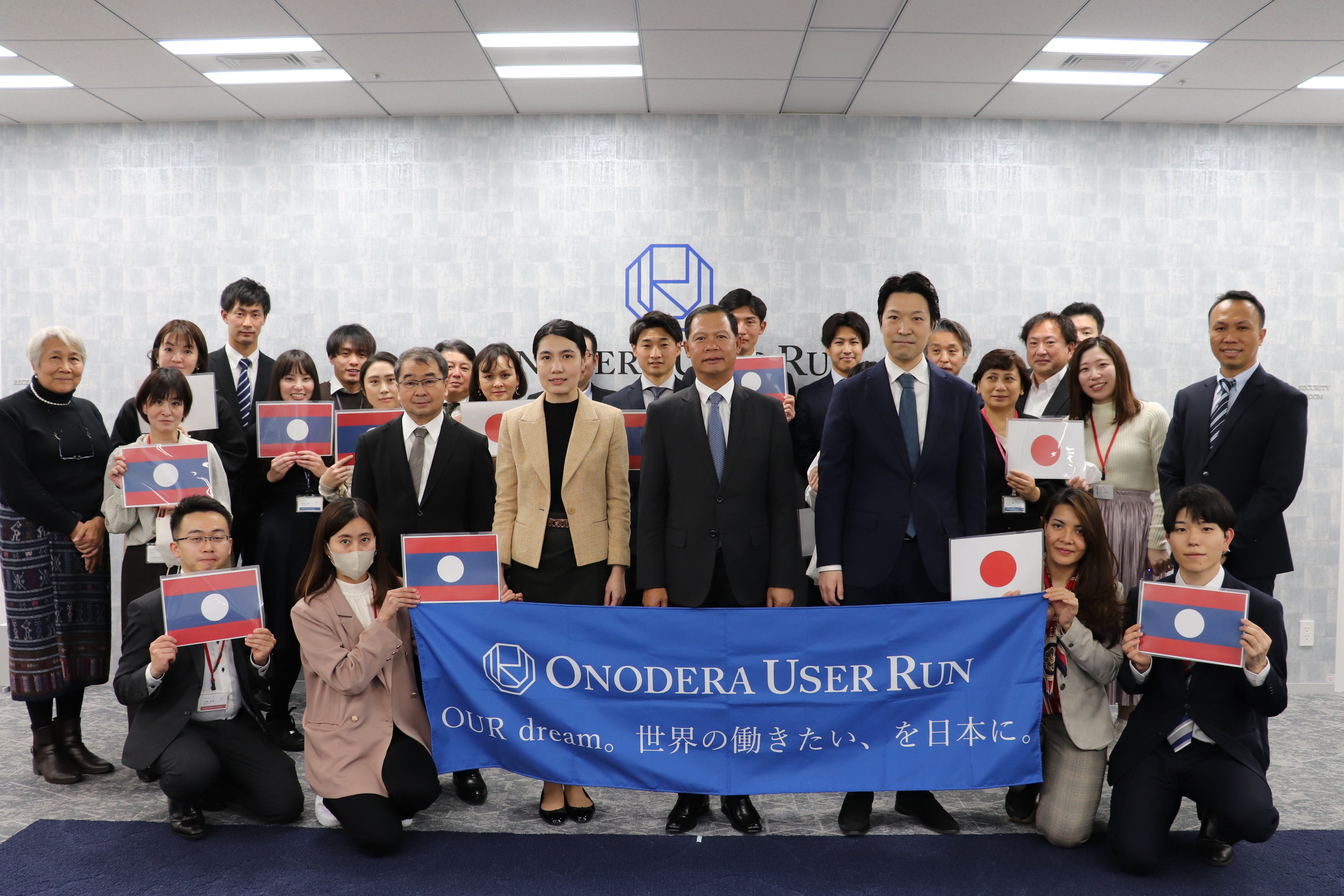 ※OURグローバル本社(OUR Global Headquarters)にてラオスと日本の国旗を持ってお迎えした様子】　