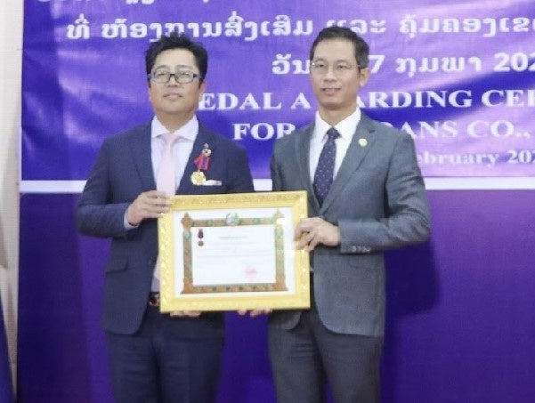 賞状を受け取るアデランス・ラオス社会長の千藤 伸一（左）とサターバンディット・インシーチェンマイ計画投資省副大臣（右）
