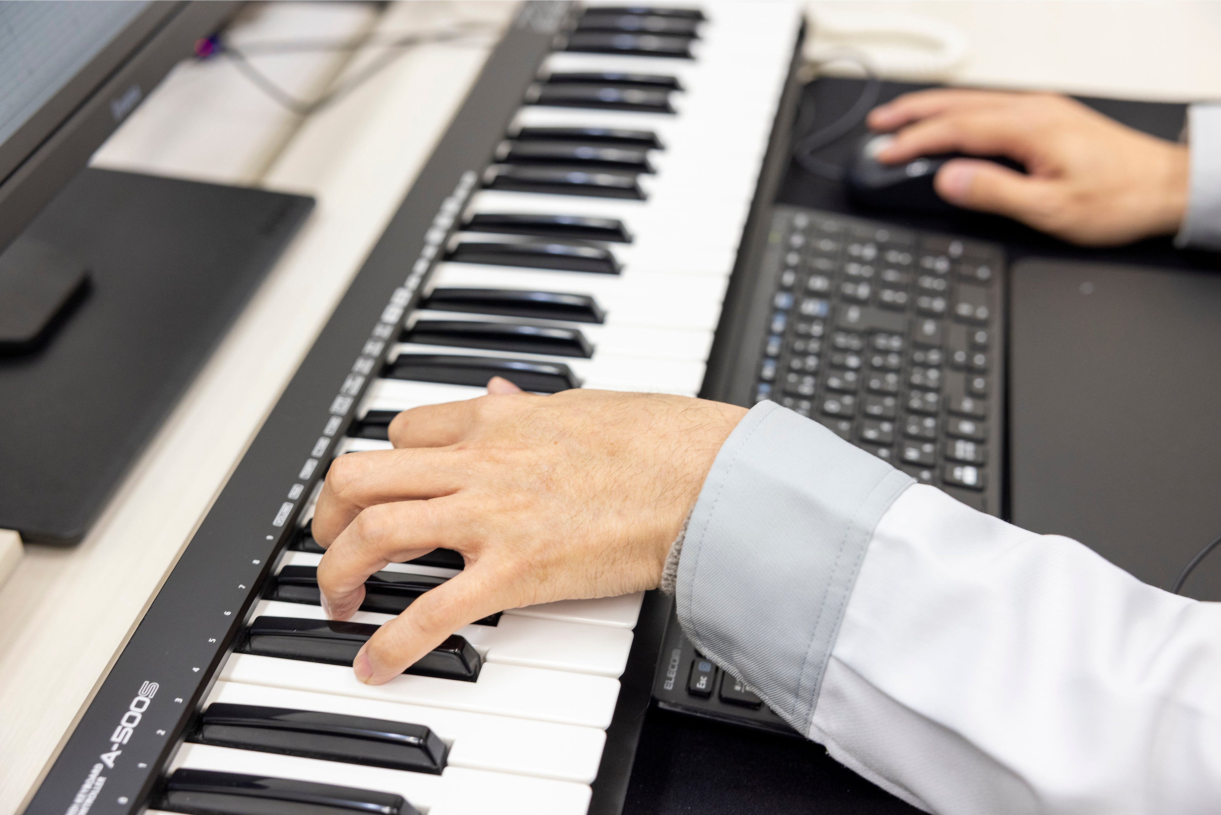 キーボードを弾きながら、PCに楽譜を打ち込む。