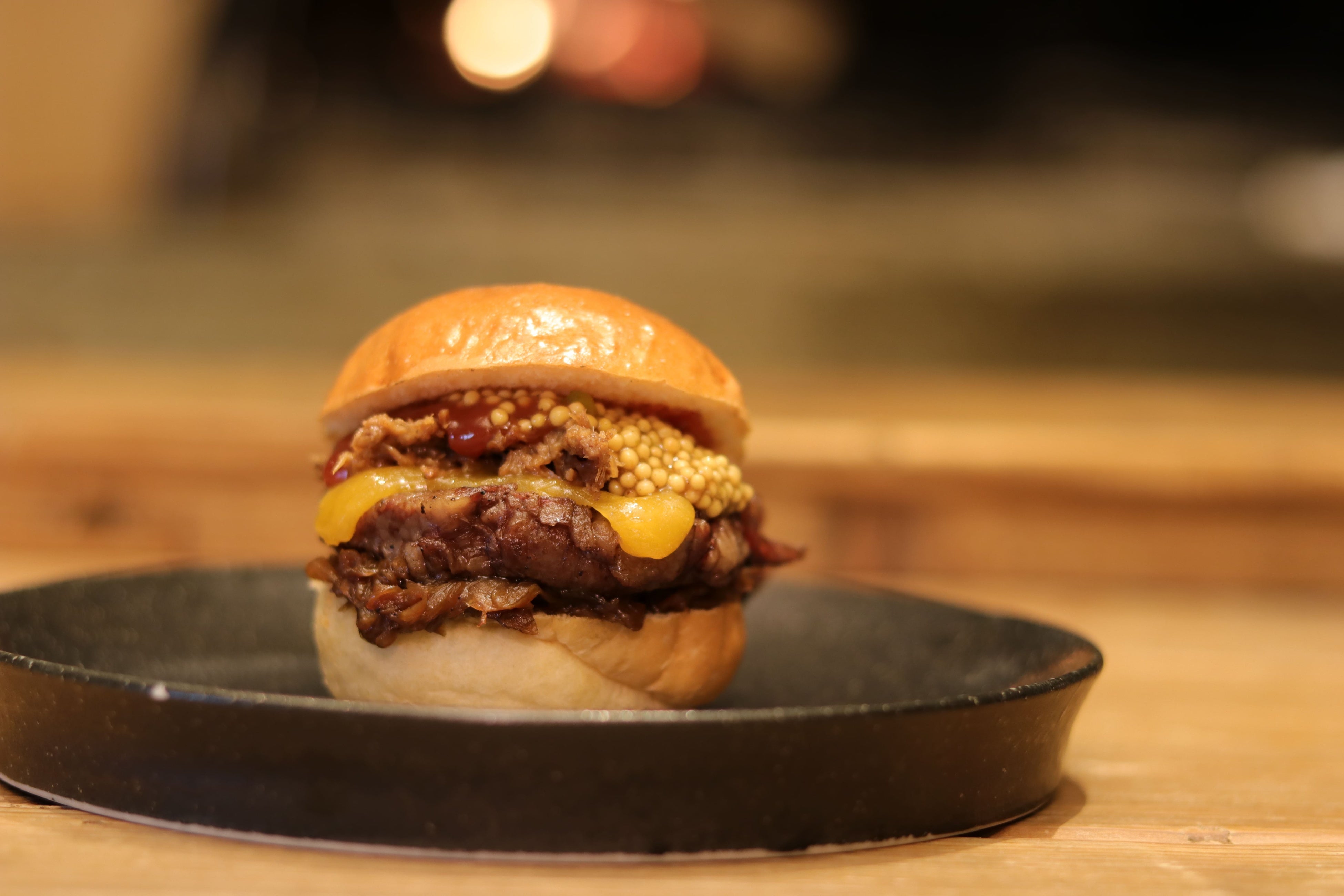 薫香かまどバーガー：「オリーブ牛肩ロースのかまど焼」と自家製コンビーフを、こだわりのバンズで挟んだ、薪の香りを纏った新感覚のハンバーガー。