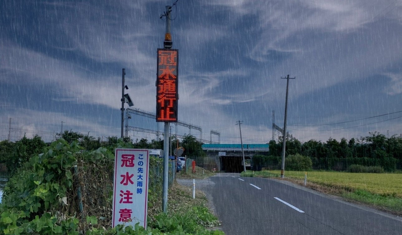■宮城県利府町の町道に設置された冠水通知型LED表示機システムと、従来の注意喚起看板　※雨天時のイメージ写真(奥に見えるのがアンダーパス部)