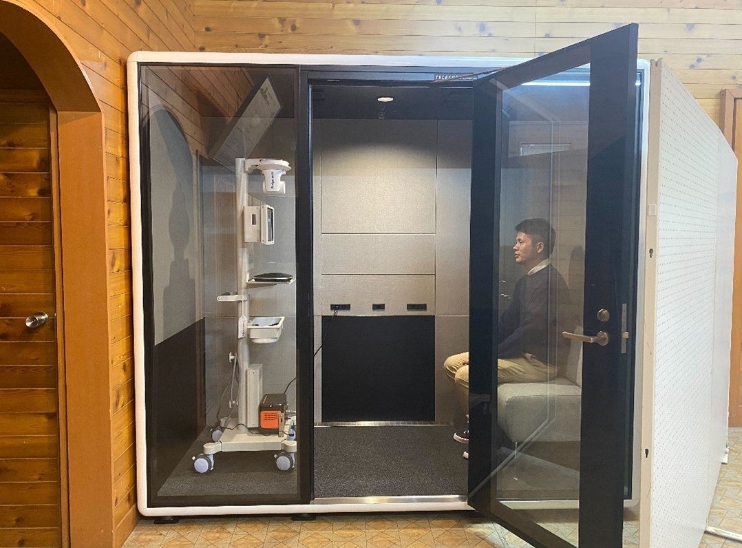 ※「あけのべ憩いの家」に設置した防音個室ブース「TELECUBE」と遠隔医療システム「Doctor Cart」  ※実際は、「TELECUBE」周辺に白いボードを設置し、患者さんのプライバシーに配慮した形でオンライン診療を行います。