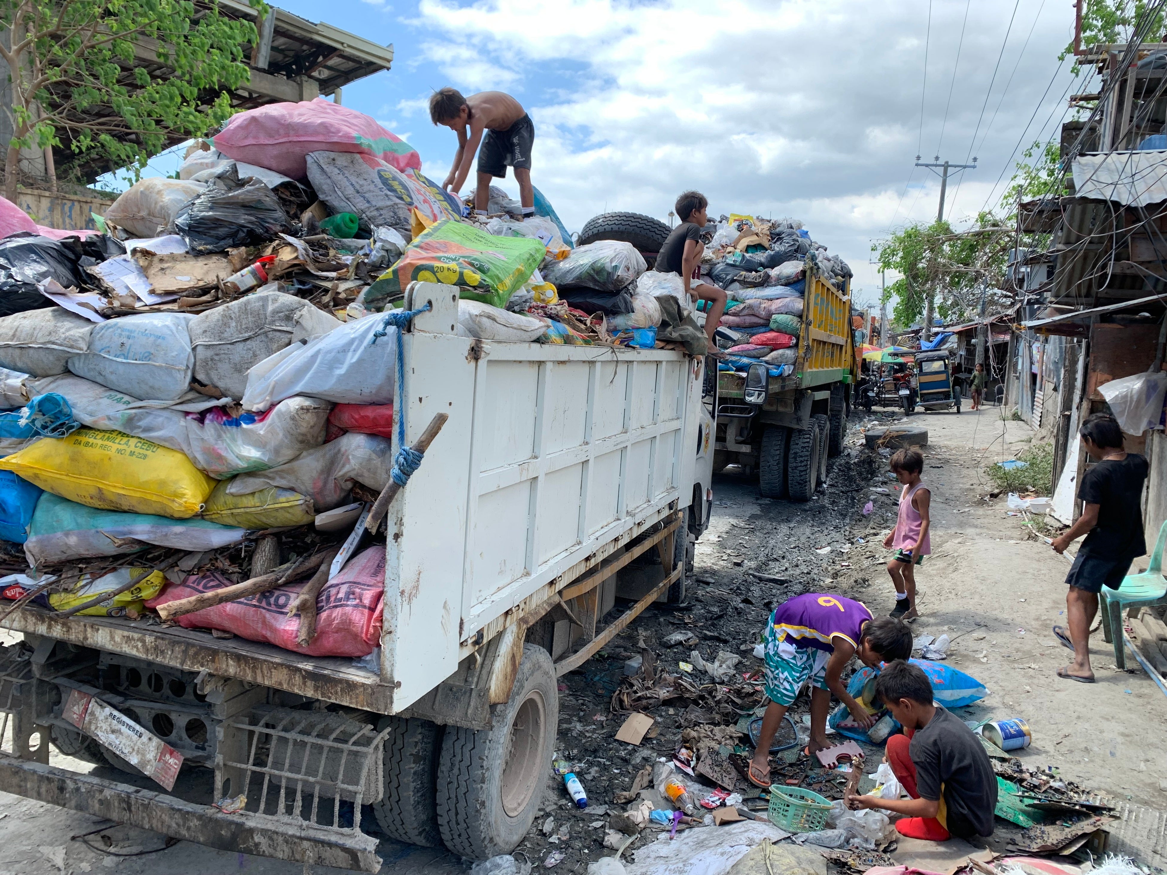 トラックに乗ってゴミを漁る子どもたち