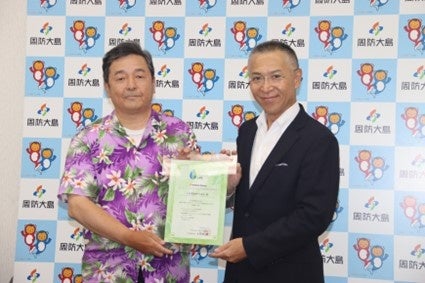 アストモスエネルギーから小松物産へ証明書を授与。左から佃一郎代表取締役社長（小松物産）、山中光常務取締役国内事業本部長（アストモスエネルギー）。