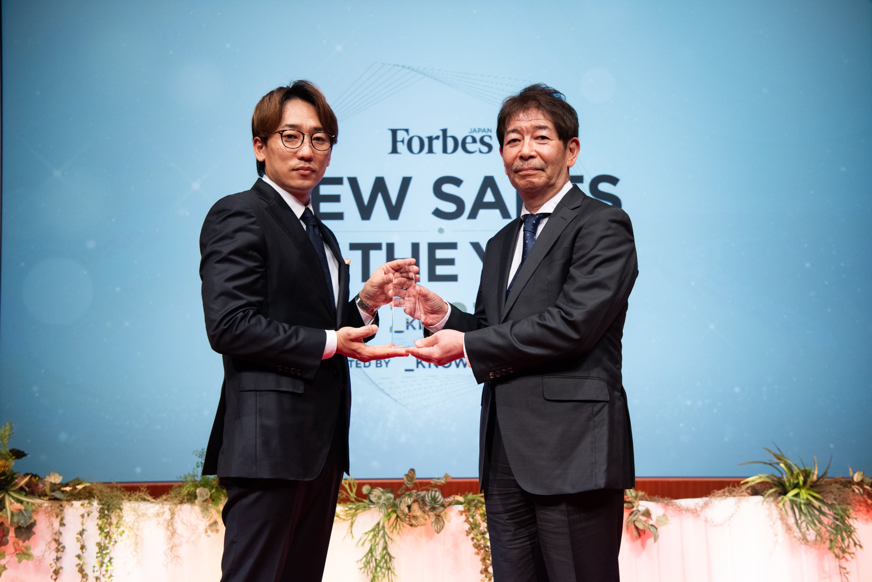 表彰式の様子（左側がリンクタイズ株式会社 取締役 CRO・Forbes JAPAN発行人 上野 研統氏、右側が当社 常務執行役員 兼 業務統括本部 本部長　横田 純平）