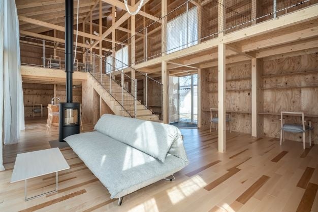 木製棚と机が一体となったKAGUユニットによる地上2階建て、吹抜け空間にあるリビングスペース © Imada Photo Service