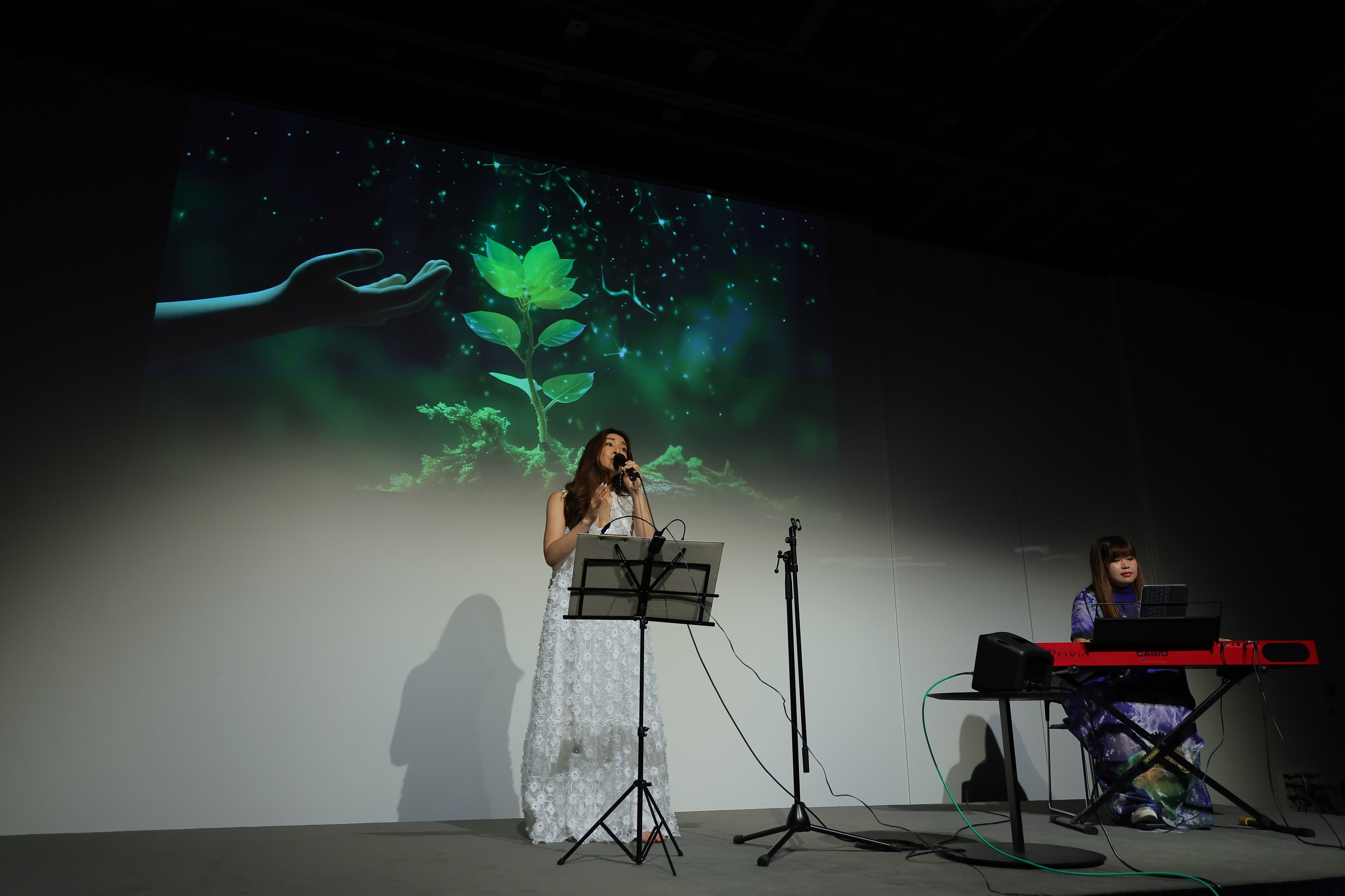 テーマソングの歌唱と登壇者でもある上山真由美氏のAIアートとのコラボレーション