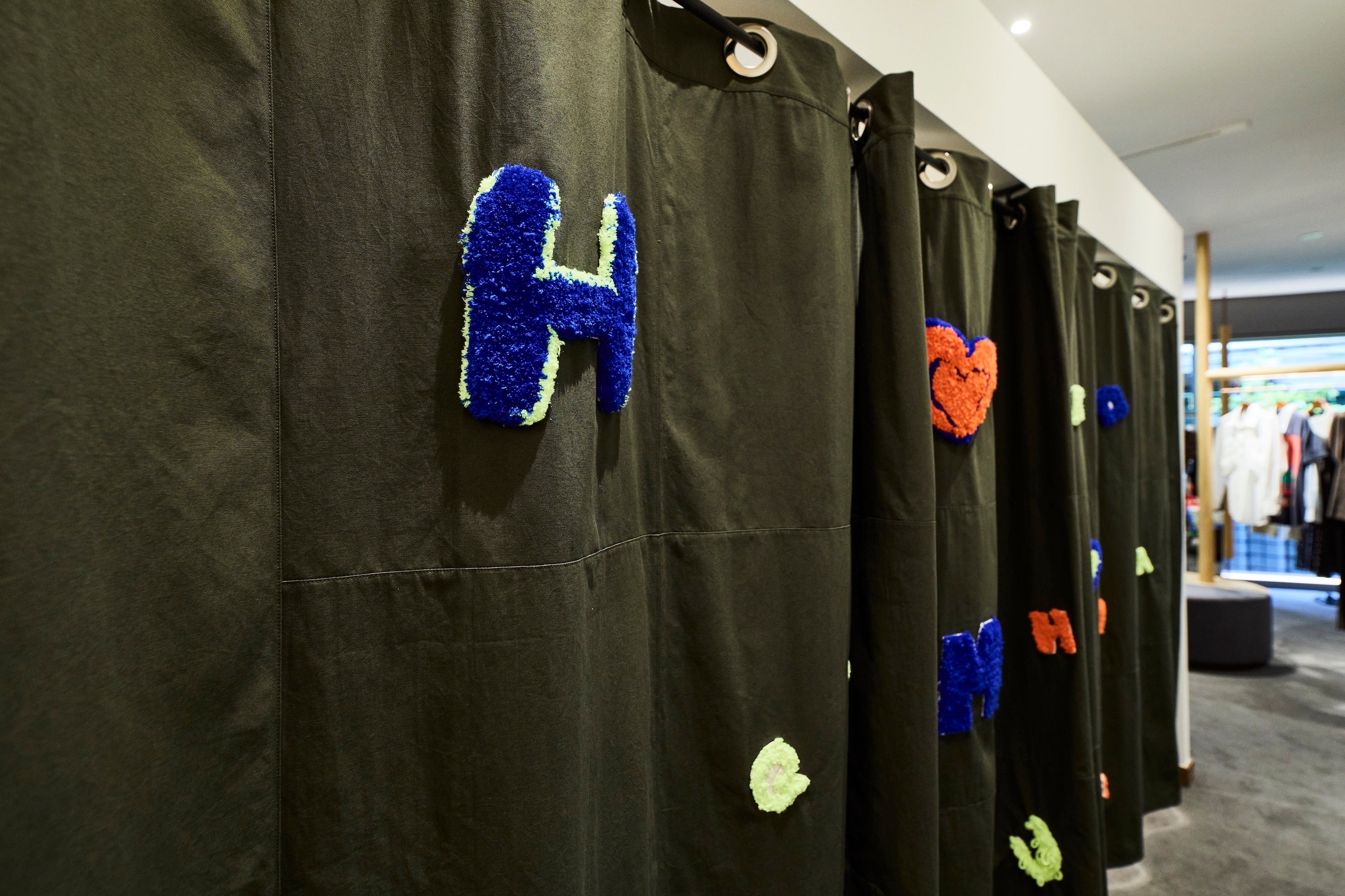 子供たちと共同制作した店舗のフィッティングカーテン。 タフティングという技法を用いて、子供たちのイニシャルや好きなマークをフィッティングカーテンに刺繍しました。