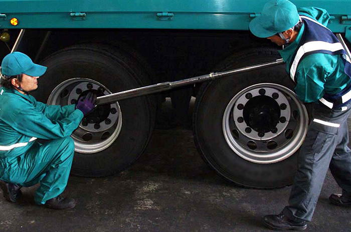 従来の大型トルクレンチでの作業風景：トルクレンチの頭部を支えてナットに位置合わせる作業者と、トルクレンチを作動させる作業者の2名で作業を行っていました。