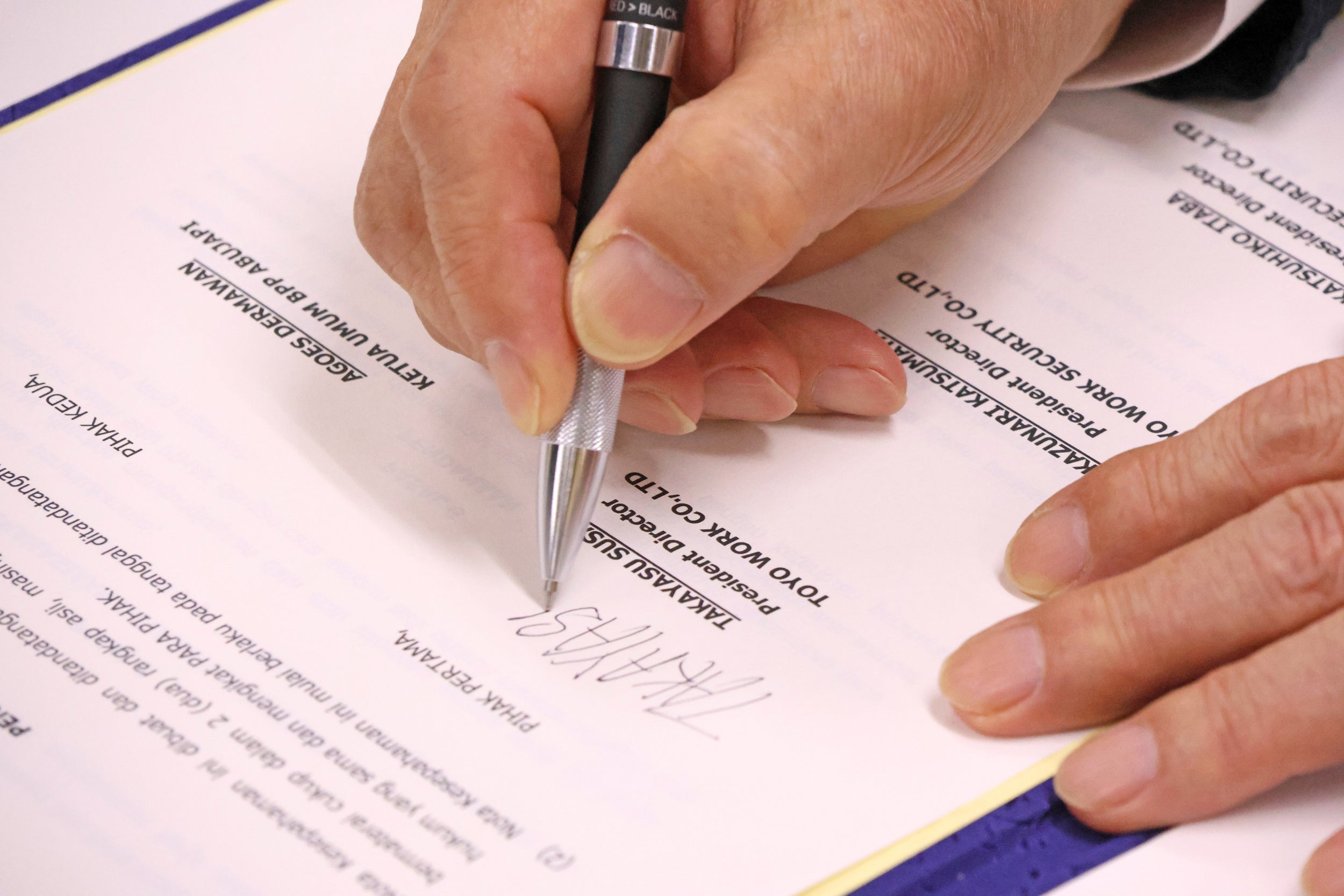 調印書にサインをする東洋ワークグループ・須佐尚康会長