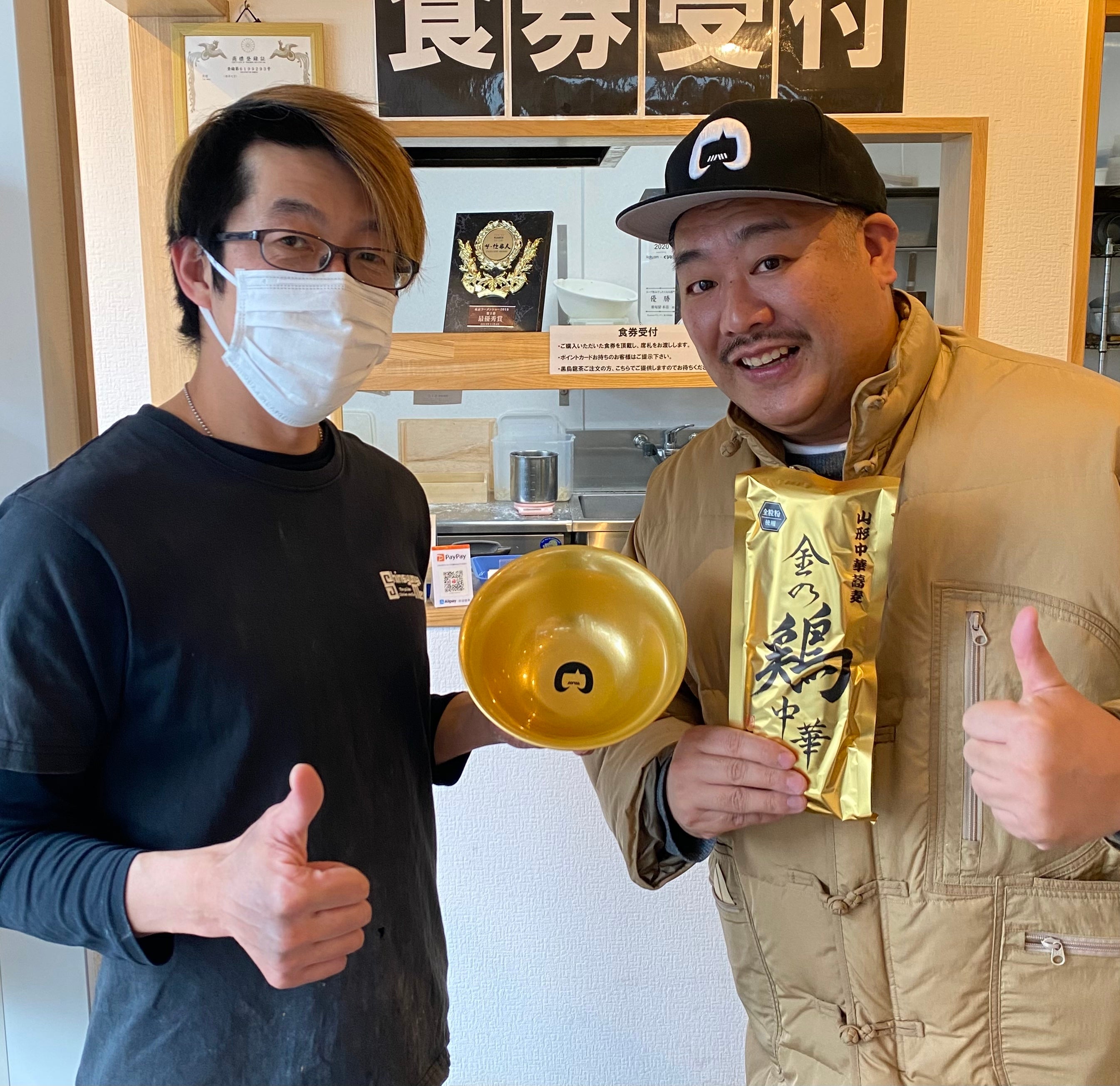 完成した丼を受け取る新旬屋新旬屋本店店長の中鉢さんとミッチーチェンさんミッチーチェンさん