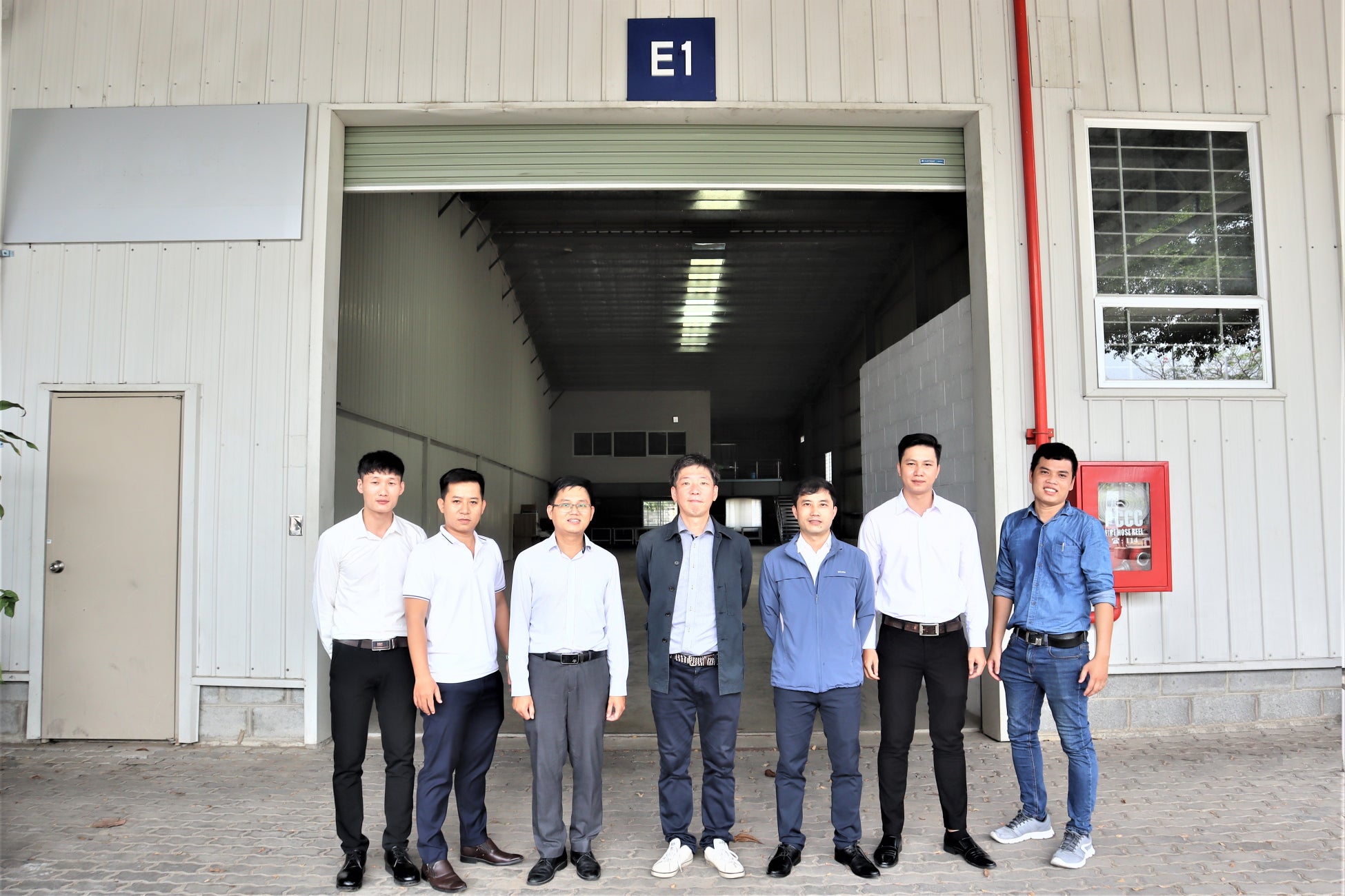 SAKAI MINA ASIA 工場前にて現地法人社長 敦賀亮(中央)と現地スタッフ