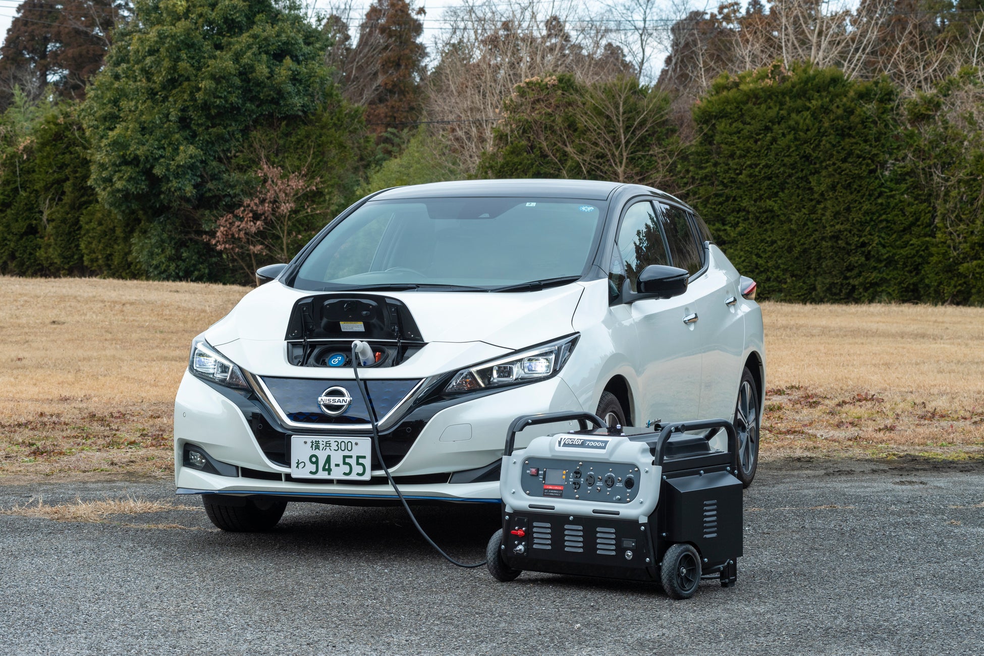 (写真=災害対策用の小型発電機を活用してEVを充電。発電機は「7000α」)