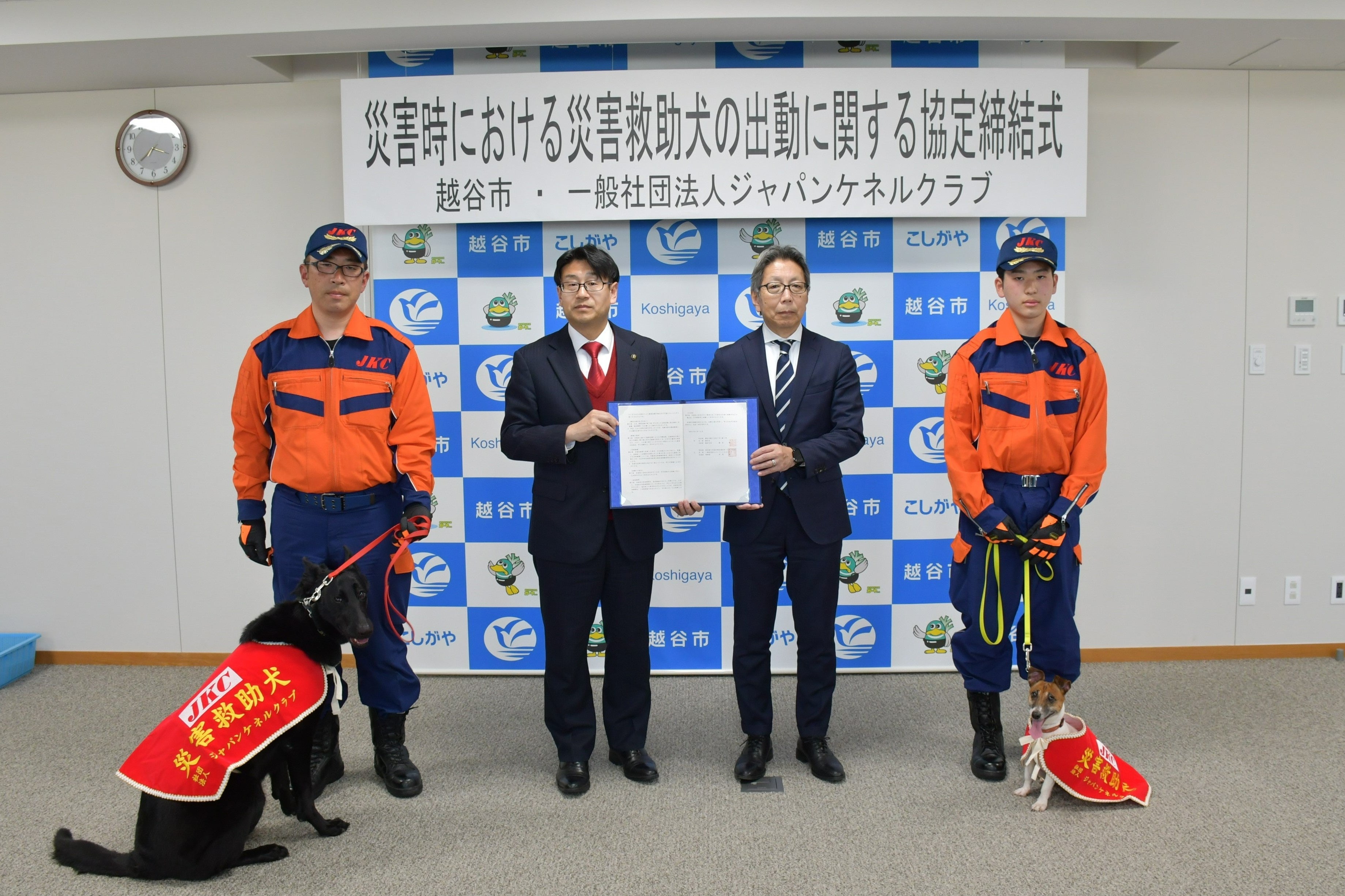 （向かって左から）災害救助犬あんみつ号、羽鳥文仁指導手、福田越谷市長、藤田事務局長、羽鳥雄太指導手、災害救助犬もなか号