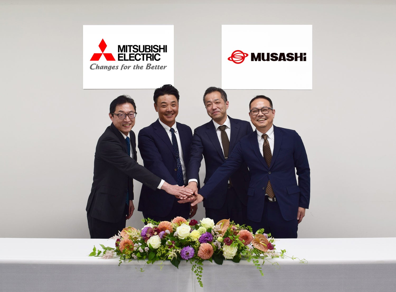 写真 左から:三菱電機 伊丹製作所 所長 都築 貴之、車両制御システム部 部長 永塚 吉生、 武蔵エナジーソリューションズ 代表取締役 髙橋 航史、 武蔵精密工業 常務執行役員 前田 大