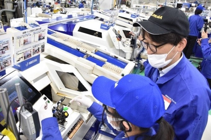 A staff member giving an instruction to a student on how to operate a machine.