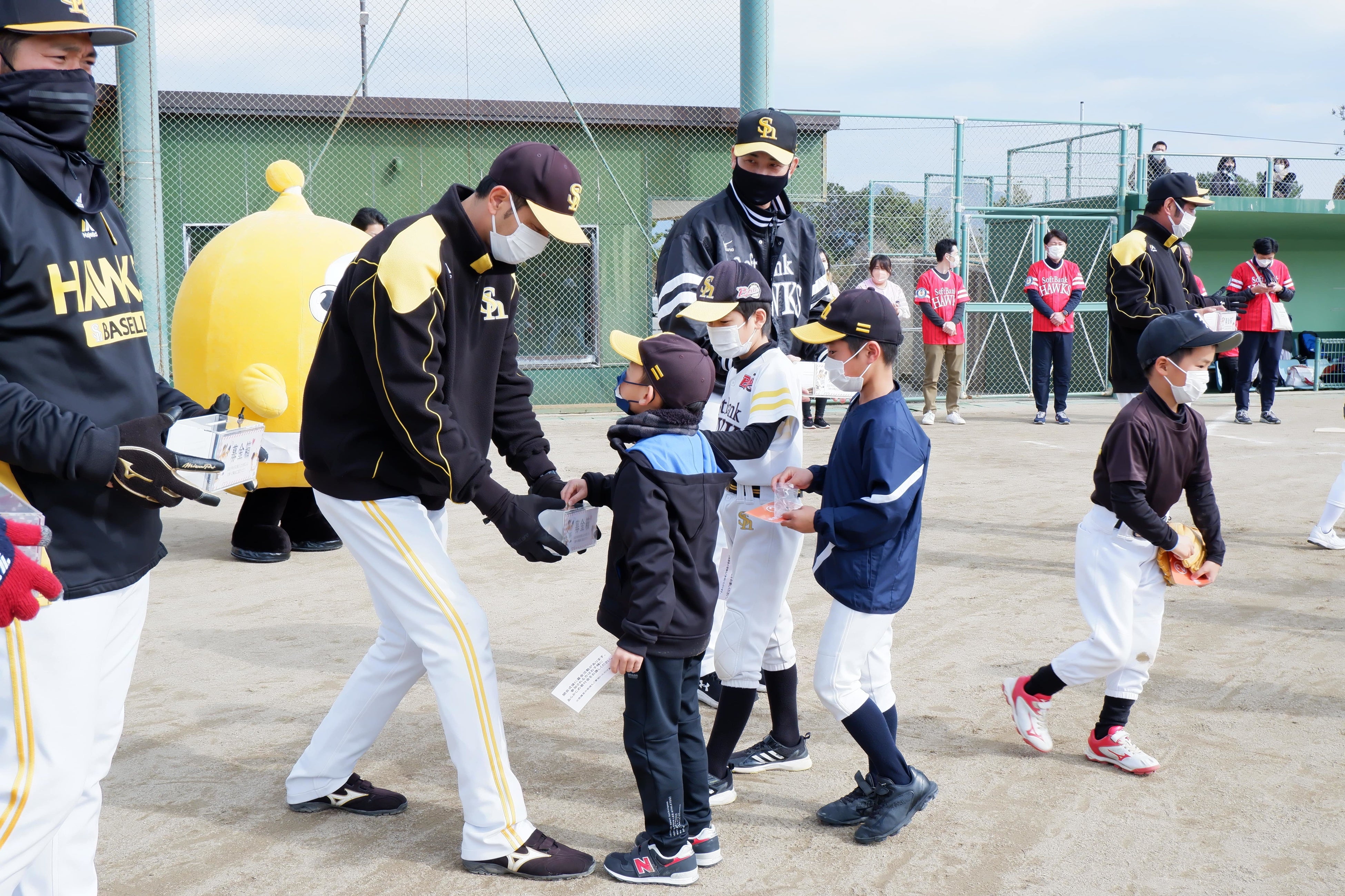 福岡ソフトバンクホークスOBたちが持つ募金箱に募金する参加者たち