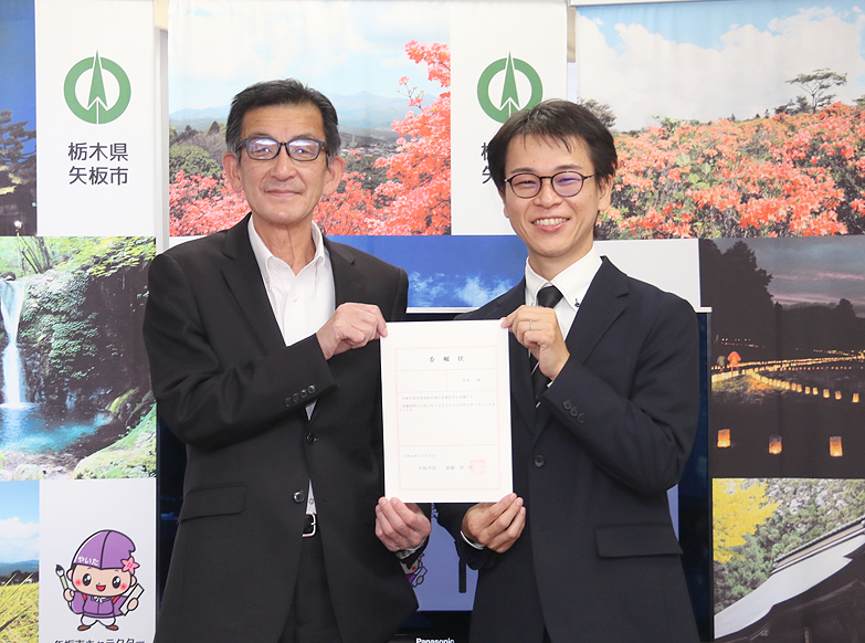 委託式で委任状を受け取る秋本（写真、右）