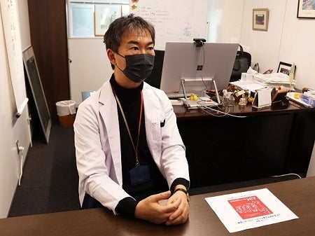 猫部からの第1回チャリティーグッズの報告書と宮崎徹氏(2023年3月一般社団法人AIM医学研究所にて)