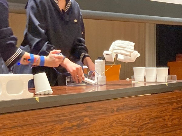 腕につけた筋電センサーで義手を操作している様子