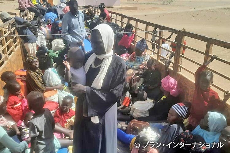 戦火を逃れトラックで移動している人々　