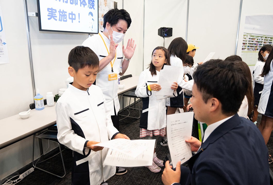 ▲日本調剤のユニフォームを着て服薬指導のロールプレイを行う子どもたち