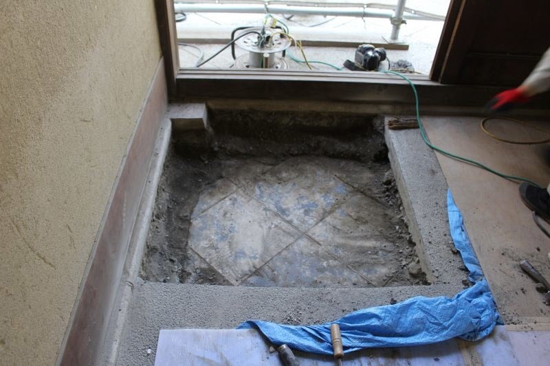 発掘された遺構。モルタルの下から黒い石張りが現れた