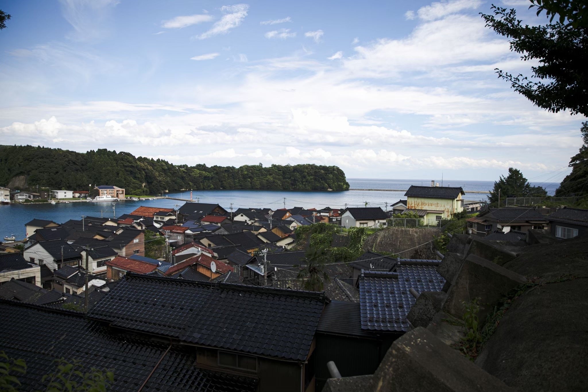 神社から見下ろす町並みの風景。遠島山と宇出津湾、また海を越えて越後の雪を冠した三嶺を遥かに望むことができます