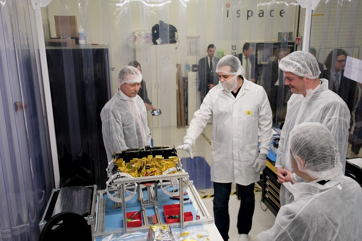 Manufacturing LabのClean Roomでエンジニアからマイクロローバーの説明を聞く様子