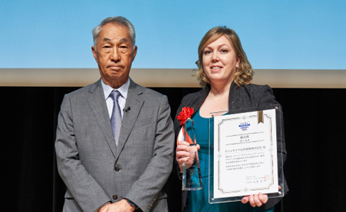 ＜総合賞表彰＞ 左：UCDA 理事長　在間 稔允 氏 右：マニュライフ生命　チーフ・マーケティング・オフィサー カーラ・ハートライト