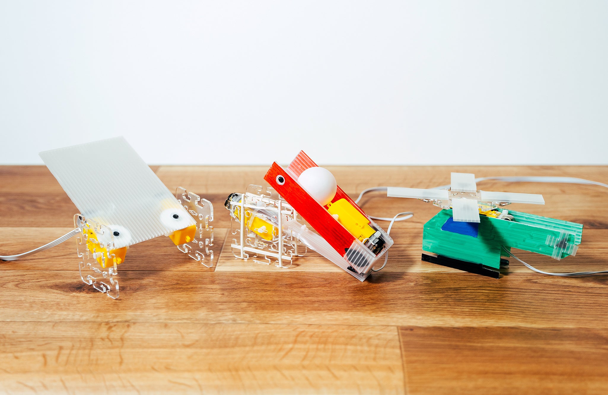 作例：左から、2輪走行できるロボット、ピンポン玉を飛ばせるロボット、ヘリコプターのようにプロペラが回るロボット