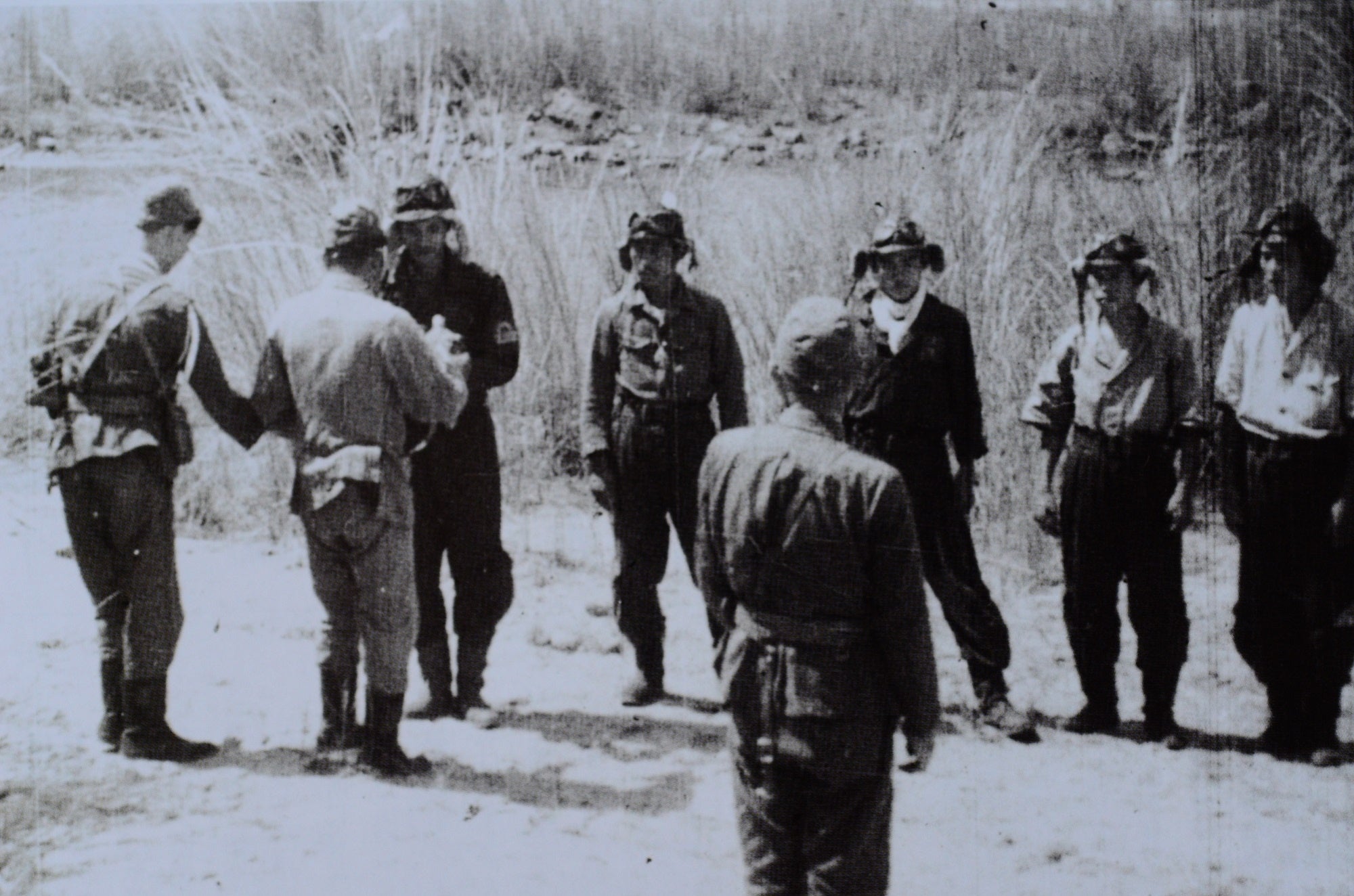 昭和19年10月20日、特攻隊編成の日。フィリピン・ルソン島のバンバン川の河原で別杯。手前の後ろ姿は大西中将。向かって左から、門司主計少佐、二〇一空副長・玉井中佐（いずれも後ろ姿）、関大尉、中野一飛曹、山下一飛曹、谷一飛曹、塩田一飛曹