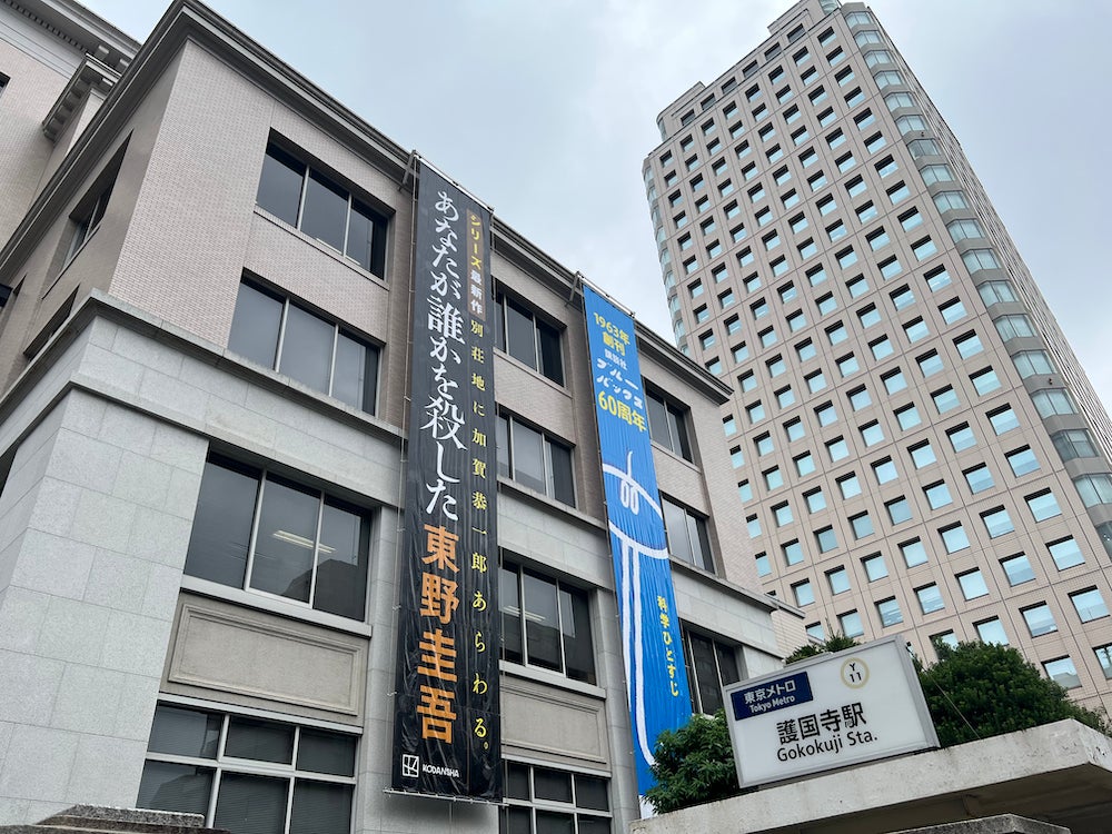 懸垂幕のイメージ(2023年10月上旬撮影)。 写真左が講談社・本館。撮影時に掲出されていたのは東野圭吾氏の新刊『あなたが誰かを殺した』と、自然科学系新書レーベル「ブルーバックス」60周年記念の懸垂幕。写真右は講談社・高層棟。