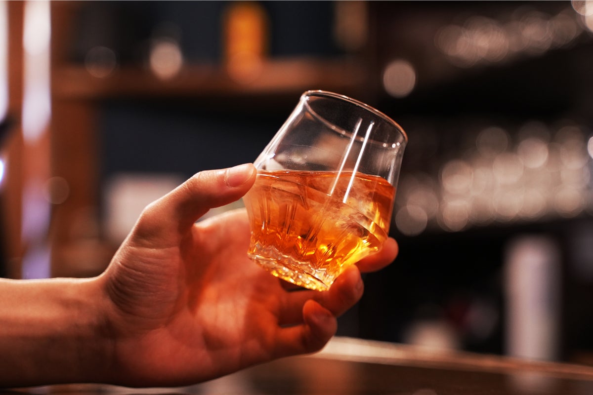 画像の説明:左手で氷の入った香りの良い酒を傾けている様子