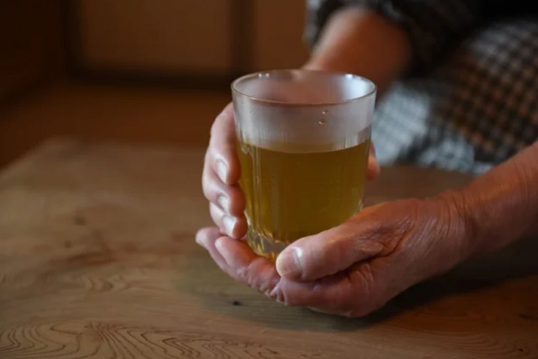 画像の説明:あたたかいお茶の入ったグラスを両手に持った様子