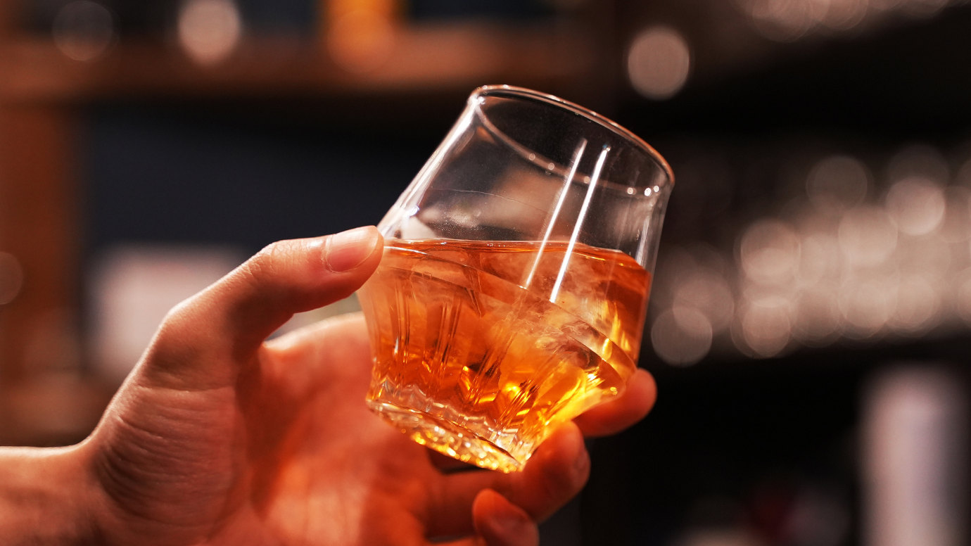 画像の説明：左手で氷の入った香りの良い酒を傾けている様子