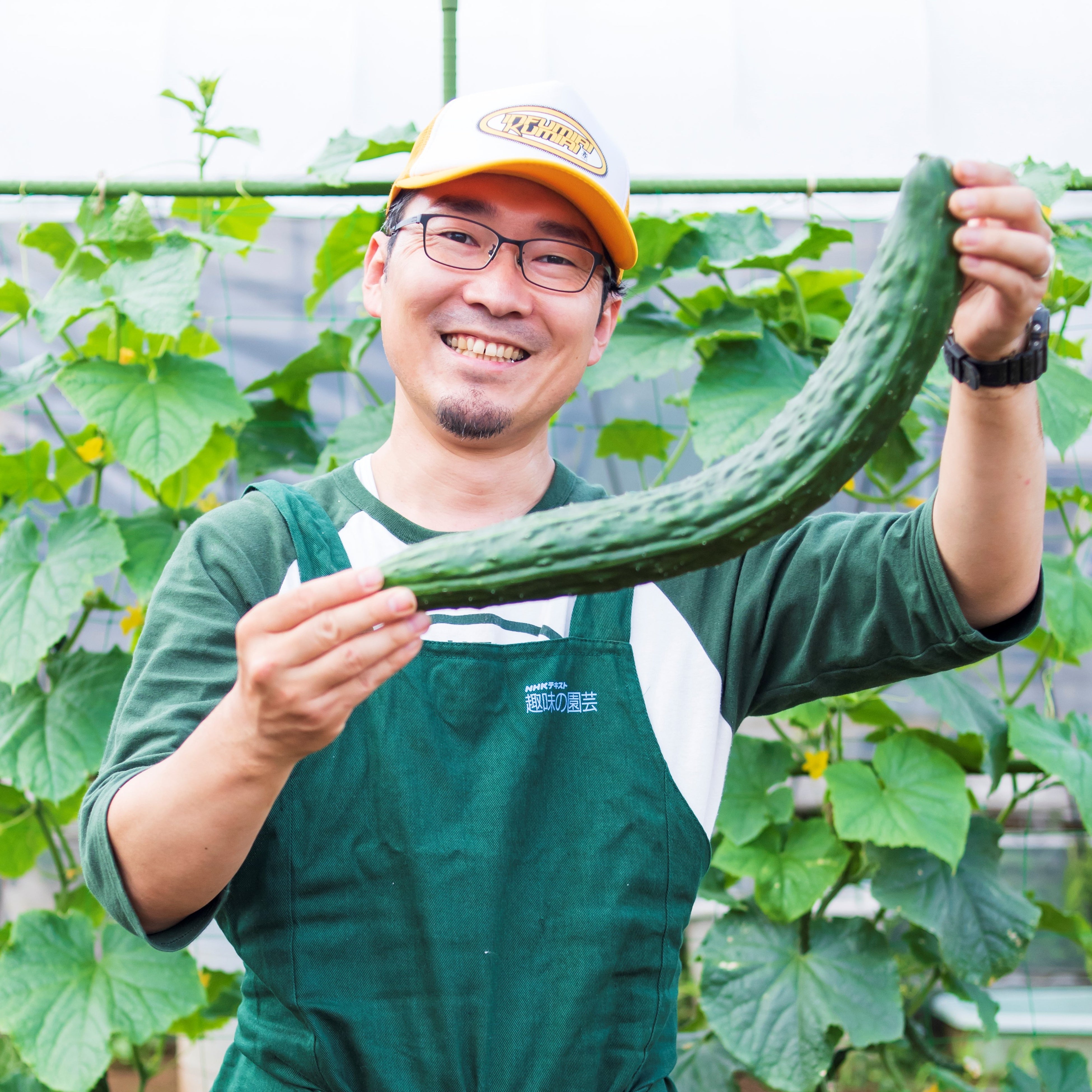 『やさいの時間』編集長・山本耕平（とり遅れて巨大化したキュウリを手に）