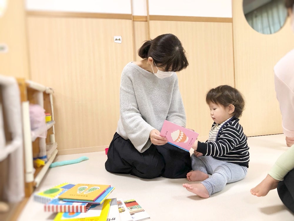 （自分で選んだ絵本を読んでもらう０歳児、「もう１回」と催促することも）