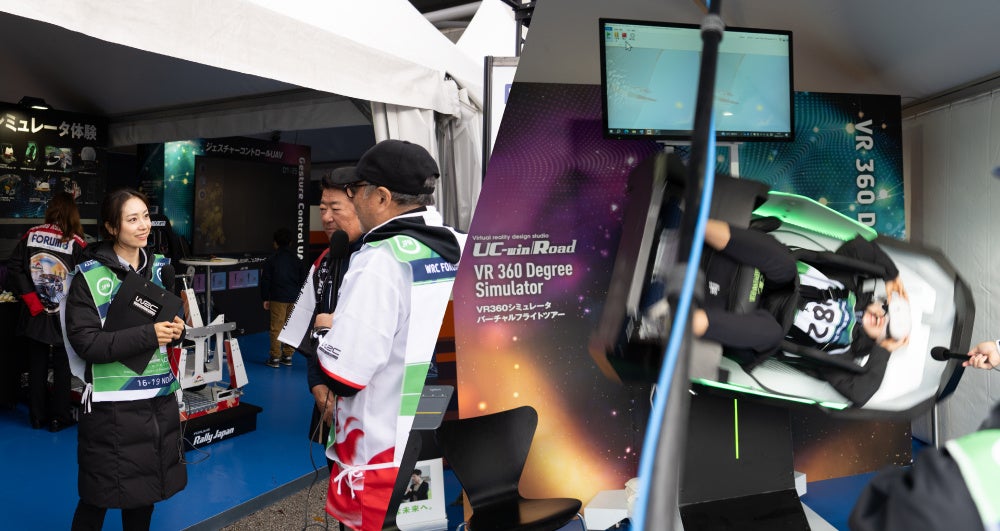 弊社出展ブースでJSPORTS3生放送の取材、キャスターの栗田さんは360 °シミュレータも体験