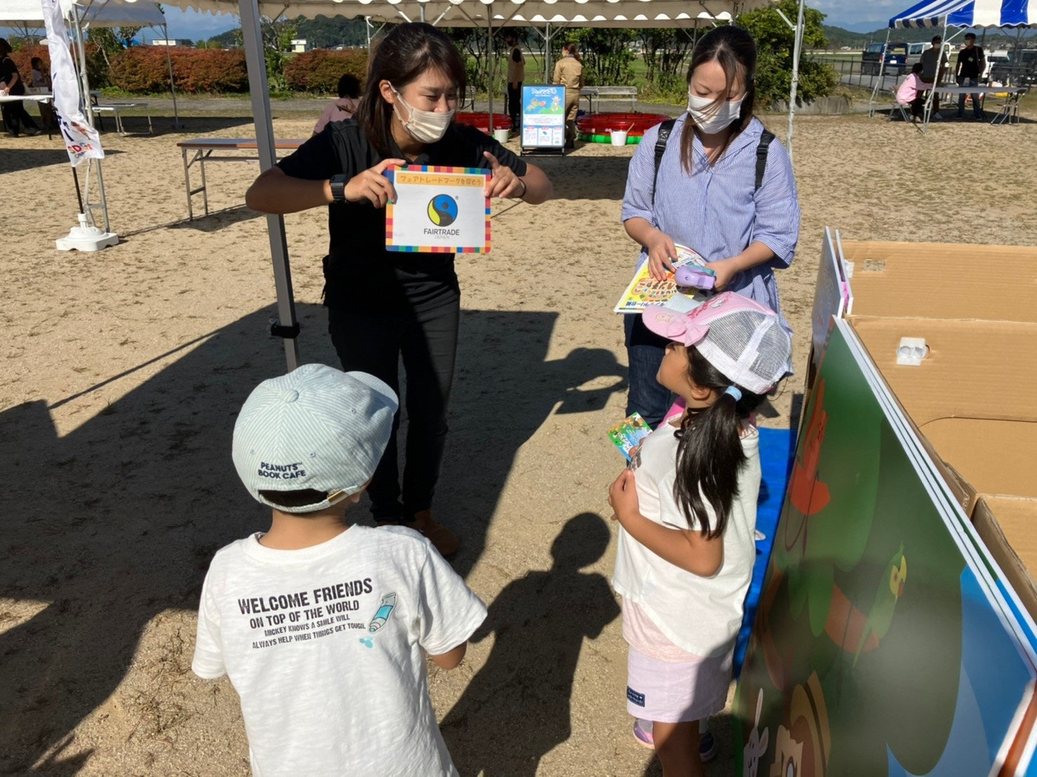 ワークショップ終了後にフェアトレードマークについての説明を聞いている写真です。ワークショップを楽しみながらSDGsついて学ぶ機会もあります。