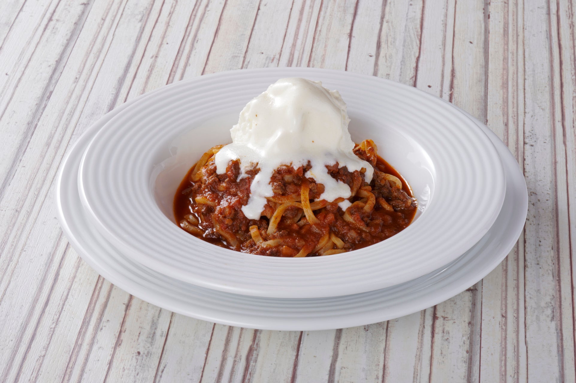 もちもち生パスタのミートソースにホイップ状にした自家製バタークリームをたっぷりトッピング。お客様の前でバーナーで炙って仕上げる食欲をそそる一品。