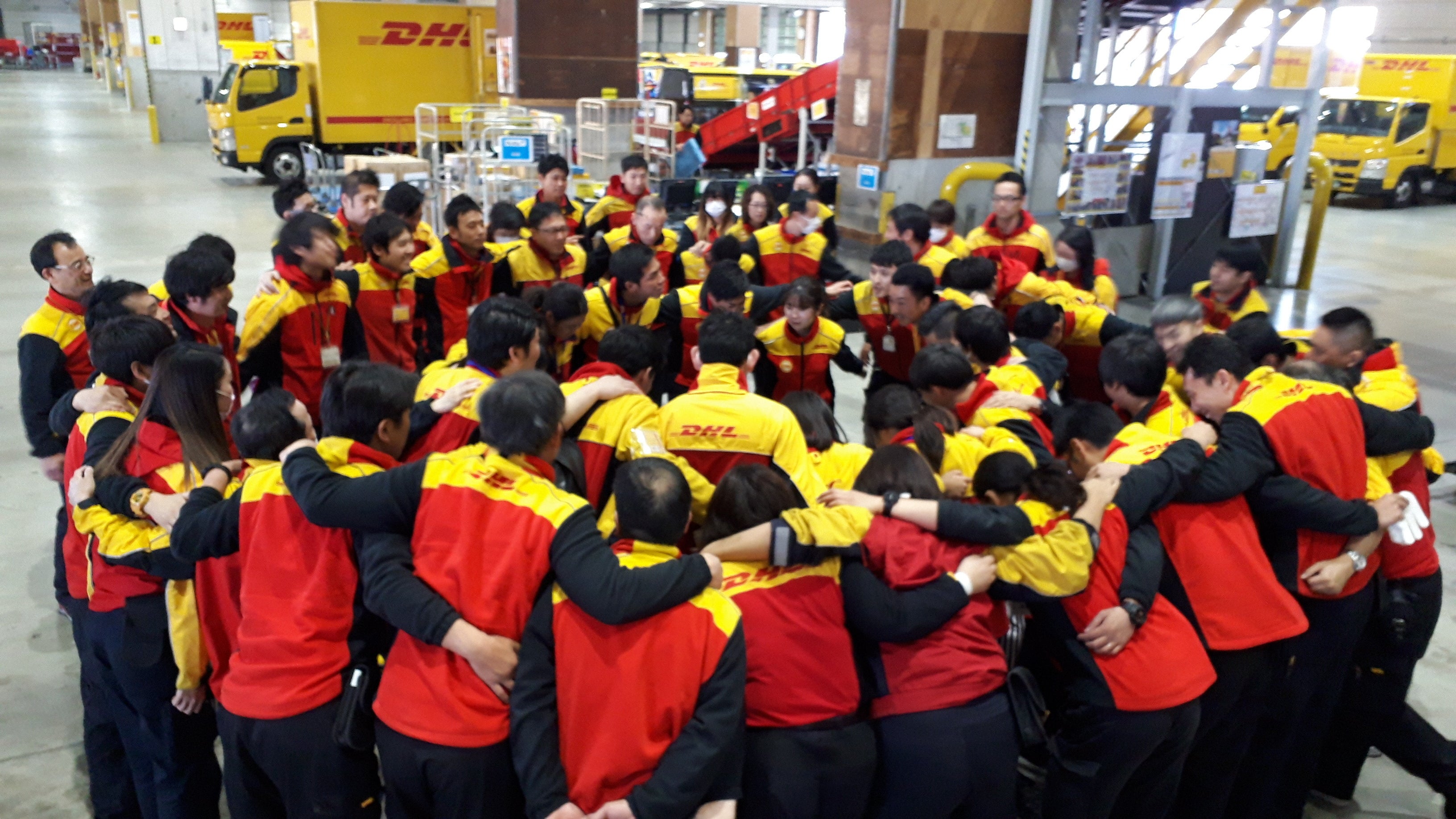 現場で円陣を組むDHL従業員たち