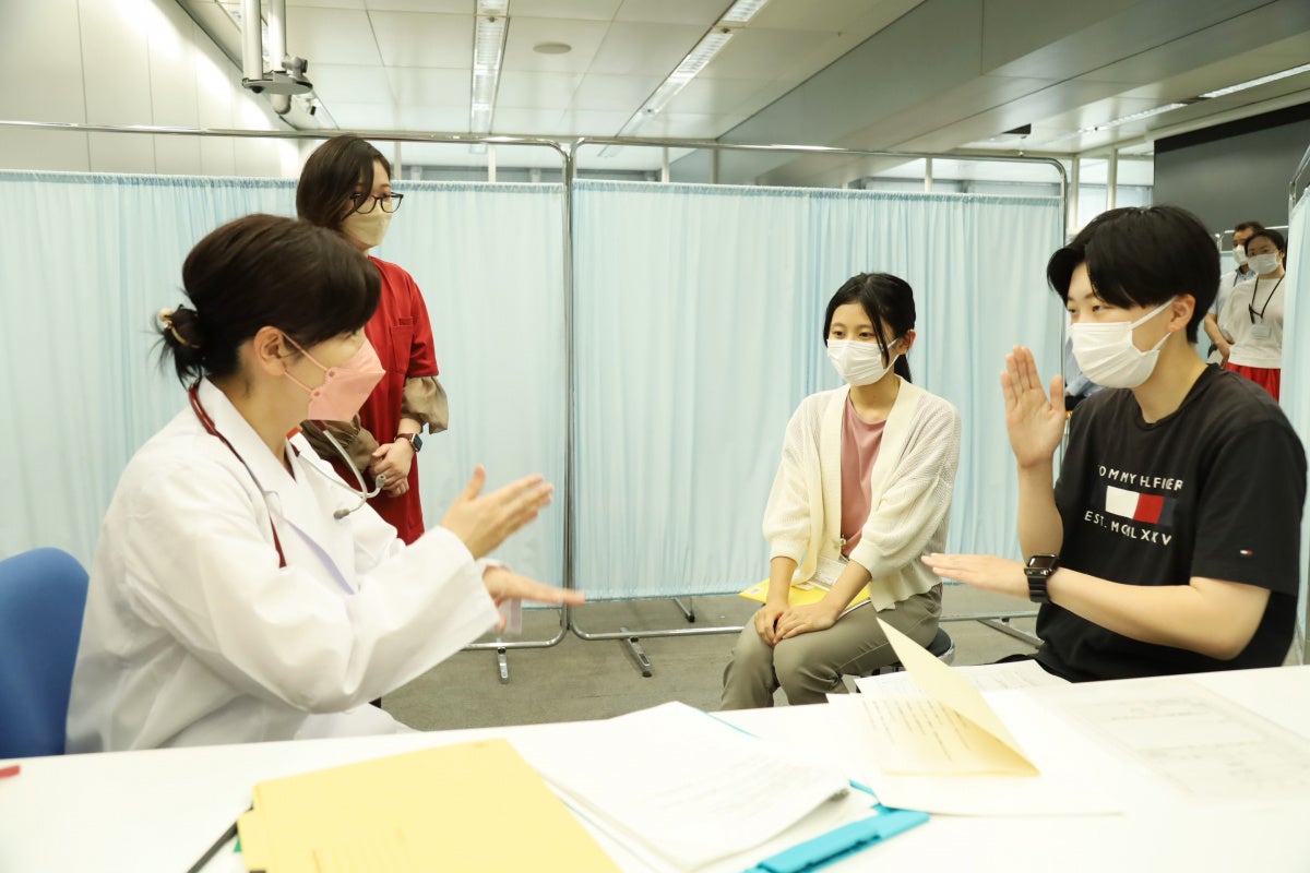 手話を使って医師とのやり取りを試みる学生（右）