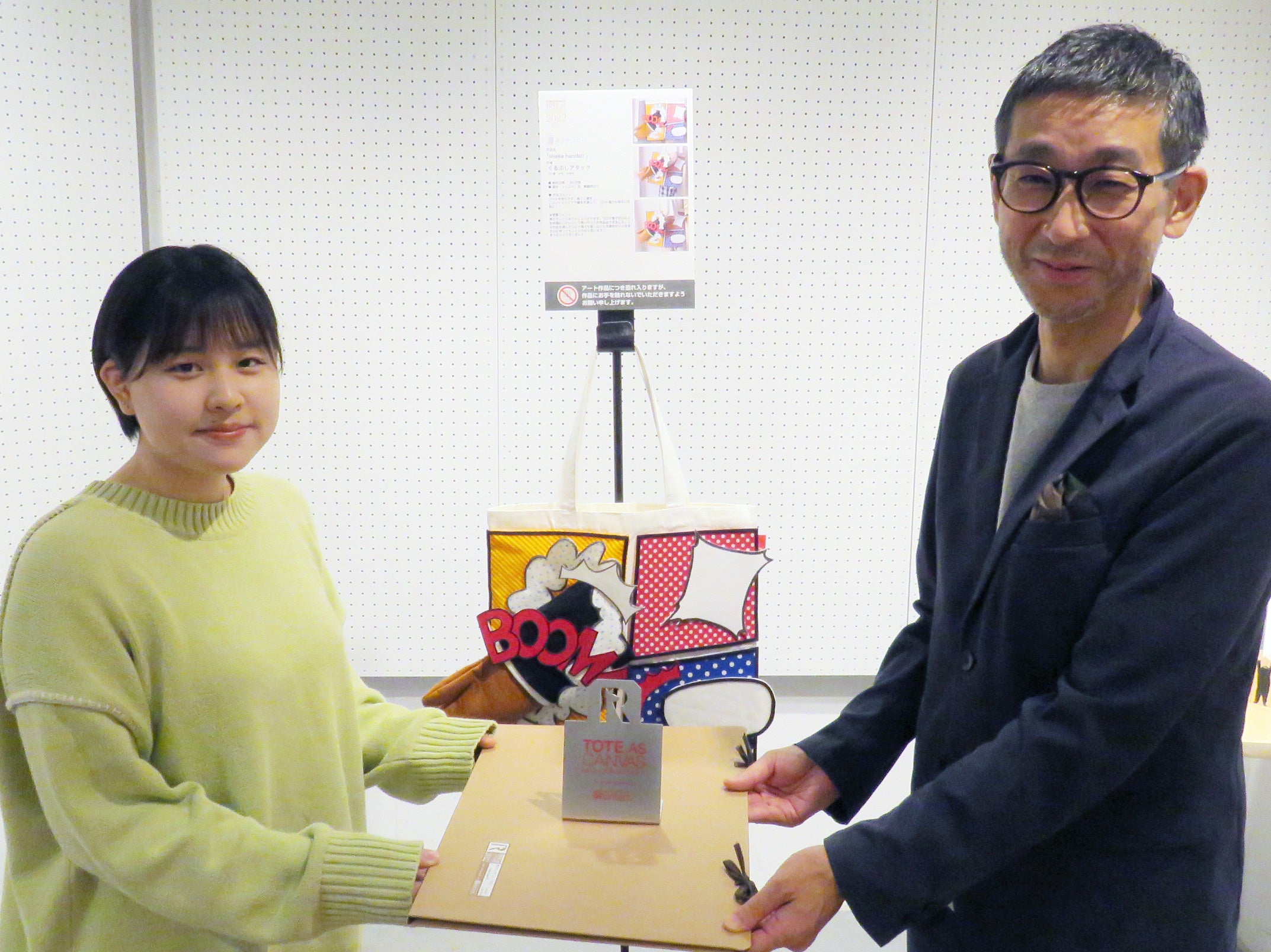 準グランプリ作品「shake hands!!」作者のくるぶしアタックさんを表彰。左 くるぶしアタックさん、右 株式会社ルートート 代表取締役 神谷富士雄