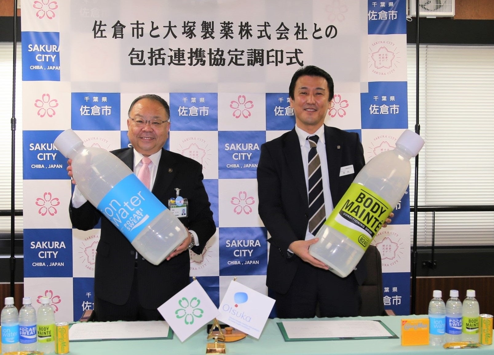 協定書に署名し、大塚製薬社商品のレプリカを掲げる西田佐倉市長（左）、大塚製薬株式会社池内支店長（右）