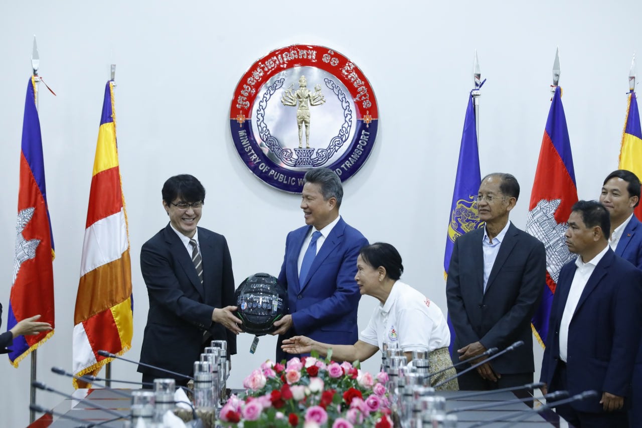 NAPS取締役 猪野(写真左）からヘルメットを受け取るMPWT Sun Chanthol 大臣(中央）