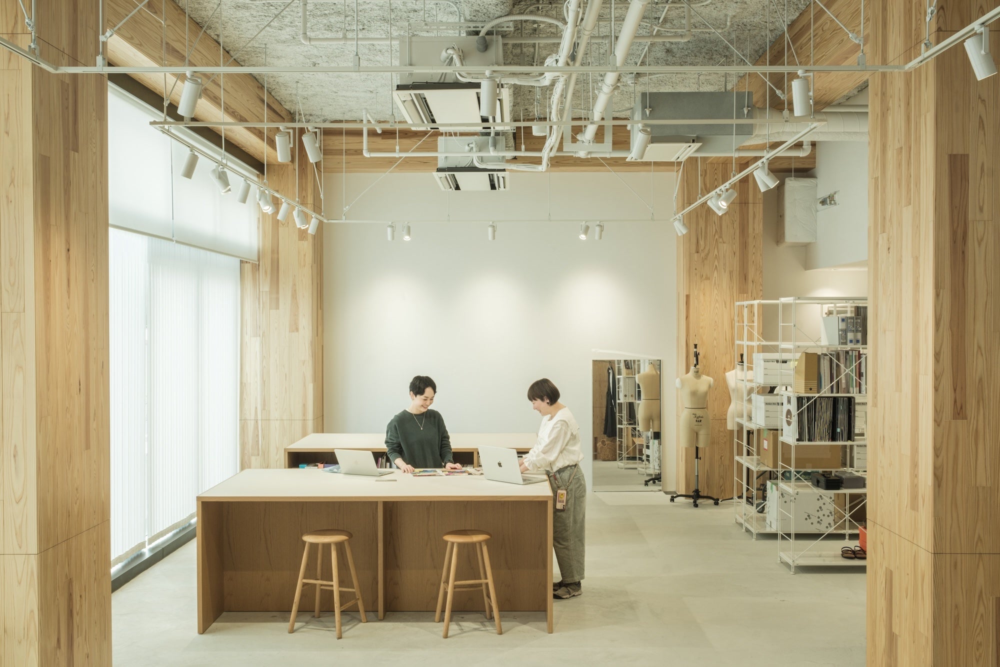 作業台：オリジナル商品の開発等で活用できる作業台。右側はストックルーム。社内全館の灯りは自然光のような光を再現できる調光システムで管理されており、朝昼晩どの時間帯でも任意の光で商品確認や撮影ができる。