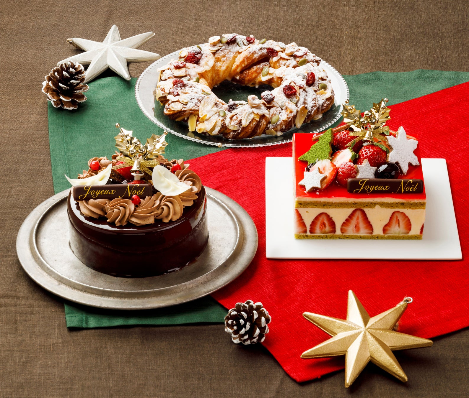 左手前は数量限定「ノエル ショコラ 2022」4号・税込み5500円、右手前は「フレジエ ノエル 2022」 4号・税込み6,300円。中央奥は12月4日までの早期予約で数量限定プレゼントする「クロワッサン リース」