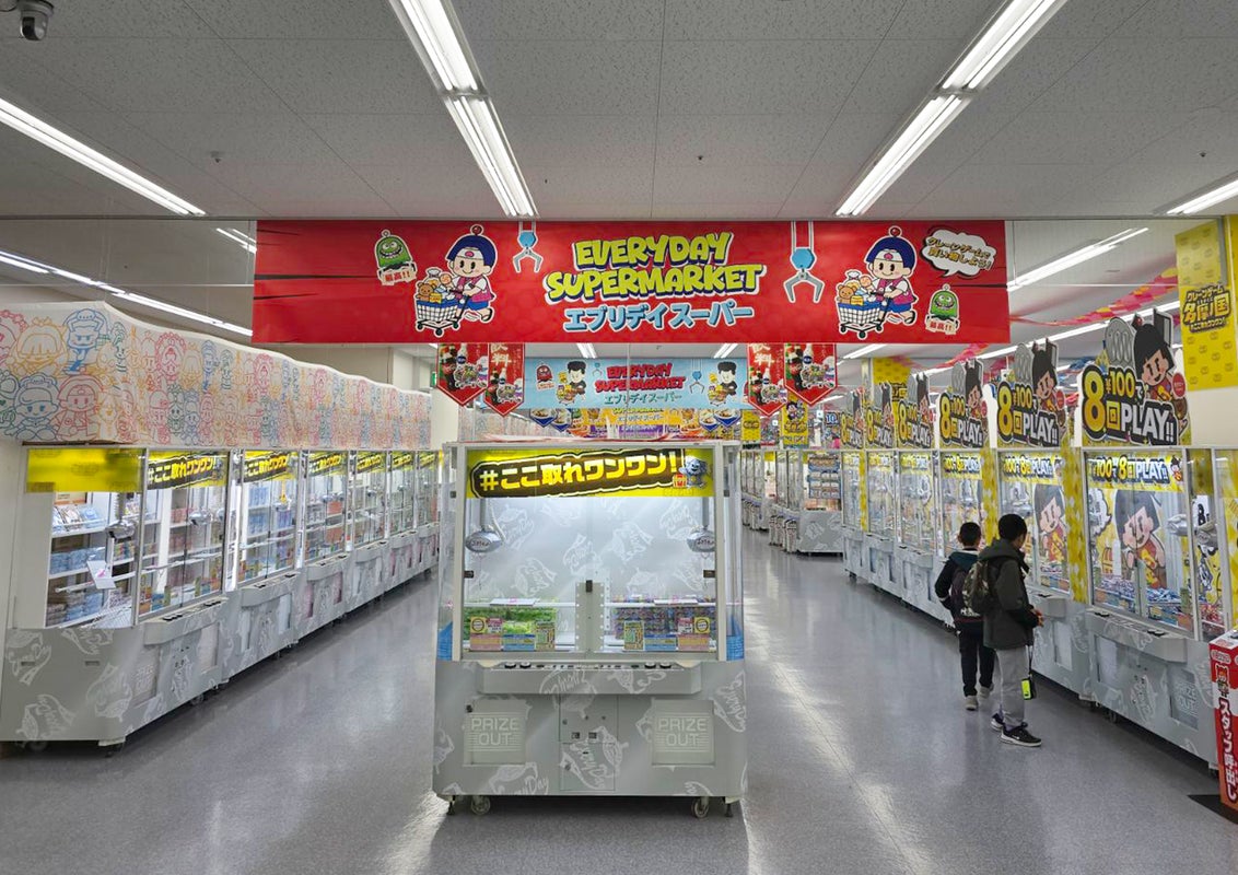 「EVERYDAY SUPERMARKET エブリデイスーパー」と書かれた赤い横断幕の下に、クレーンゲーム機が並ぶ売り場の写真