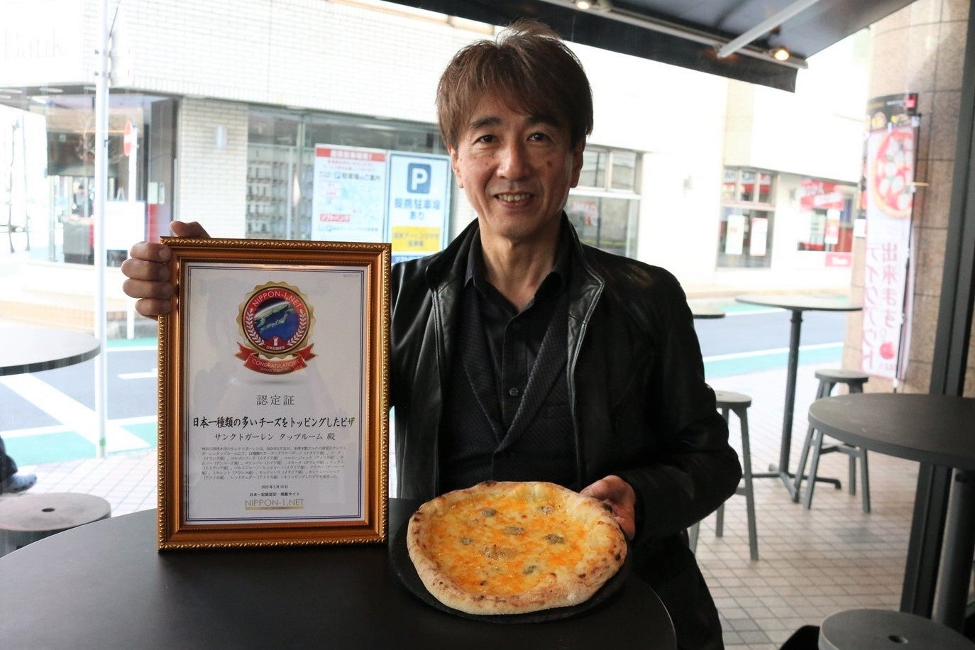 日本一認定書とピザを手にしたオーナーの岩本